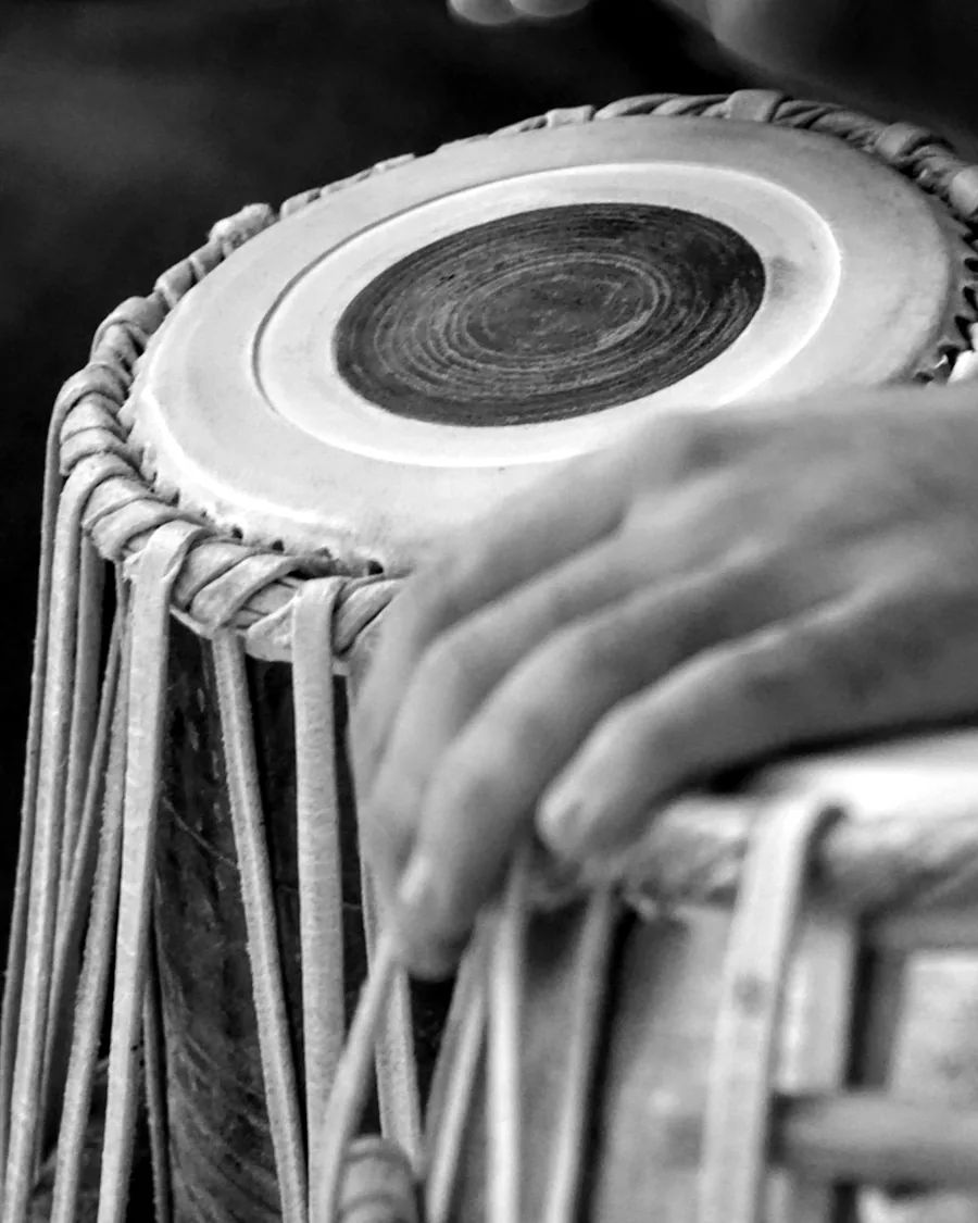 A hand mid-strike on the skin of a tabla